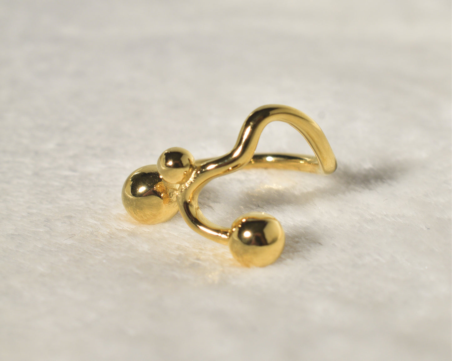 A contemporary and distinctive statement piece is the Wavy Gold Ball Ring.