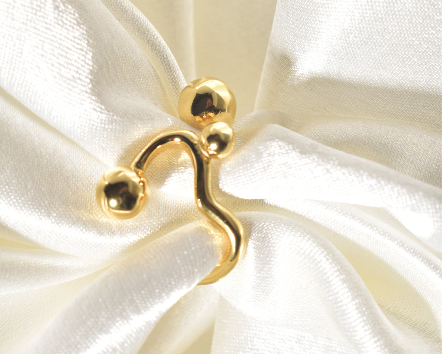 A contemporary and distinctive statement piece is the Wavy Gold Ball Ring.